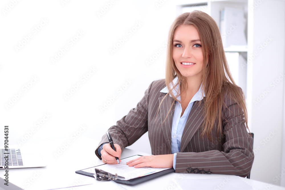 young business woman signing documents sitting at the desk on office background young business woman signing documents sitting at the desk on office background