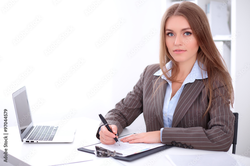 young business woman signing documents sitting at the desk on office background young business woman signing documents sitting at the desk on office background