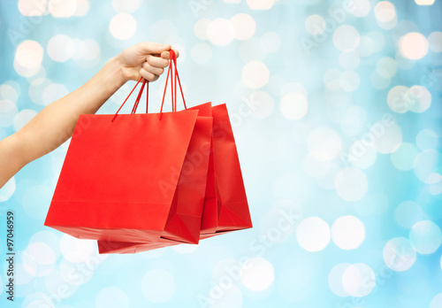 close up of hand holding red shopping bags