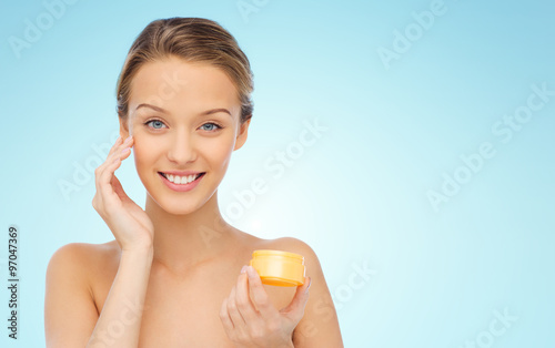 happy young woman applying cream to her face