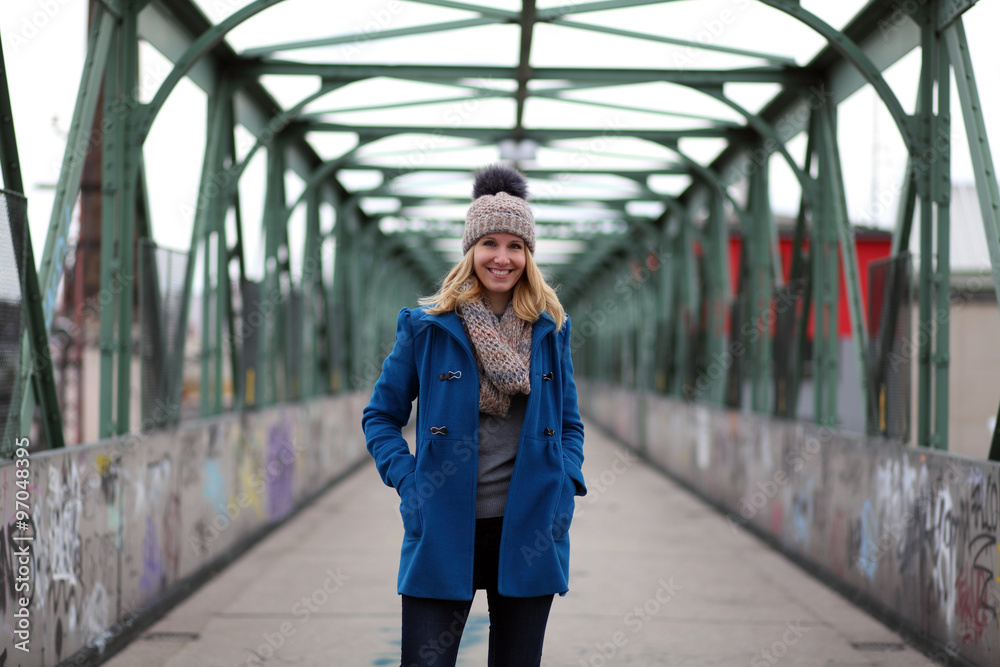 Blonde woman in blue coat and bobble hat on a bridge Blonde woman in blue coat and bobble hat on a bridge