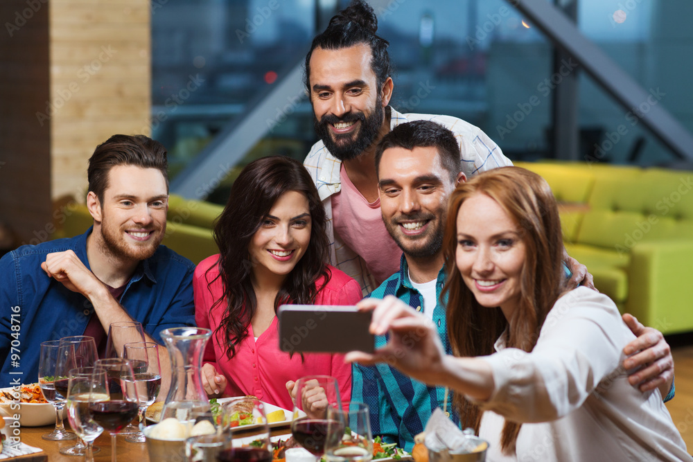 Obraz premium friends taking selfie by smartphone at restaurant