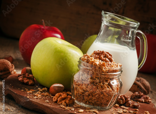 Baked muesli with nuts, milk jug, green and red apples, selectiv photo