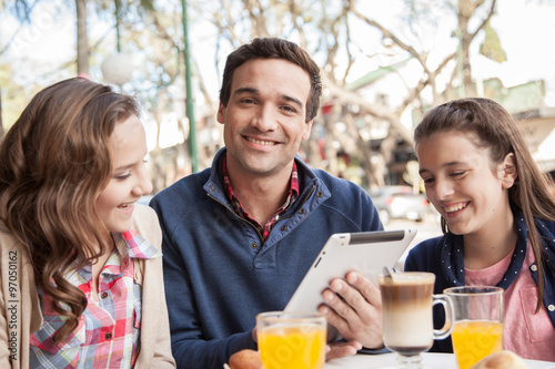 Man and young girls using the tablet in the street