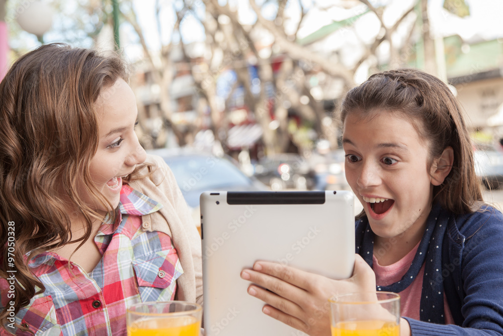 Girls using the tablet in the street Girls using the tablet in the street