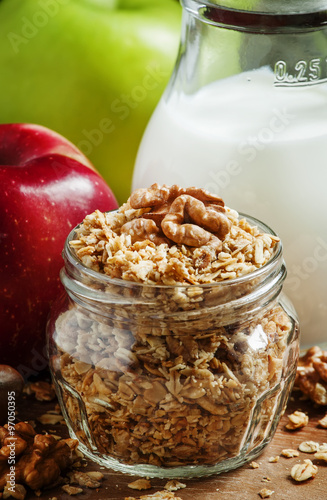 Baked muesli with nuts, milk jug, green and red apples, selectiv photo