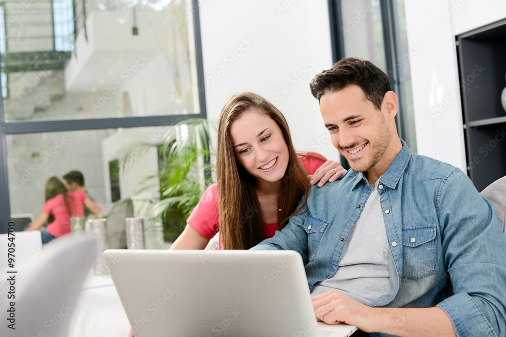 Fototapeta premium cheerful young couple man and woman in sofa at home with laptop computer