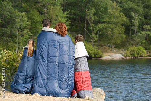 Family in sleeping bags by lake photo