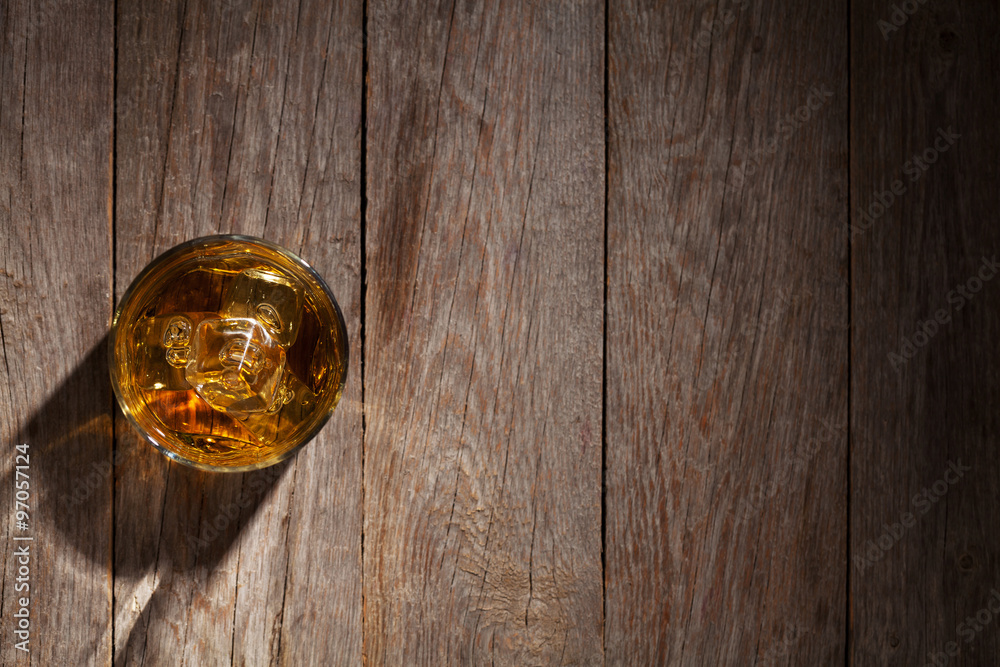 Glass of whiskey with ice on wood Glass of whiskey with ice on wood