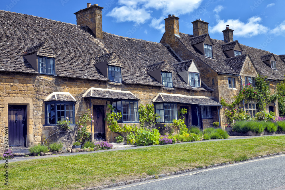 Road in an English village with golden stone traditional cottages