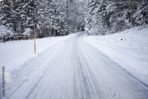 Heavy snowy countryside road. Danderous snowy and icy winter forest plowed road background. 
