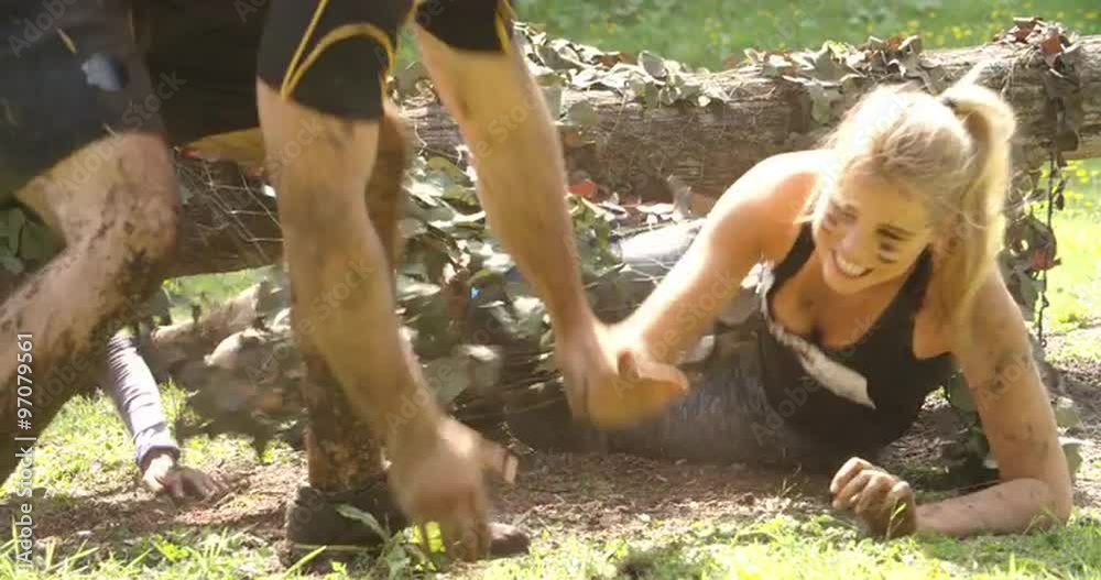 Competitors help each other through net on an assault course