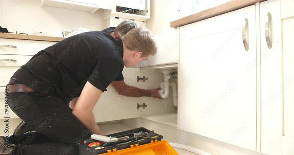 Plumber teaching apprentice to fix kitchen sink Plumber teaching apprentice to fix kitchen sink