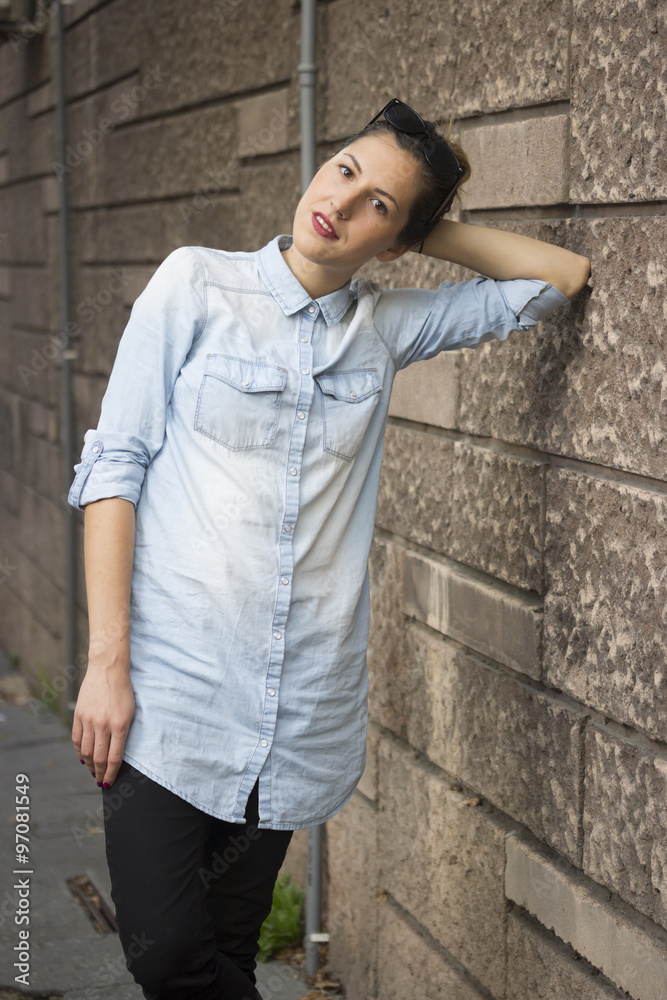 Young hipster girl portrait, leaning on wall.
