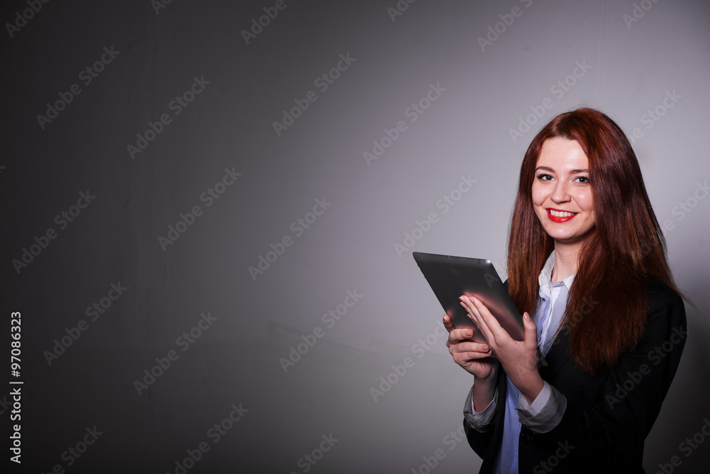 haired smiling girl using tablet over gray background haired smiling girl using tablet over gray background