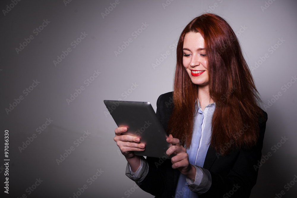 haired smiling girl using tablet over gray background haired smiling girl using tablet over gray background