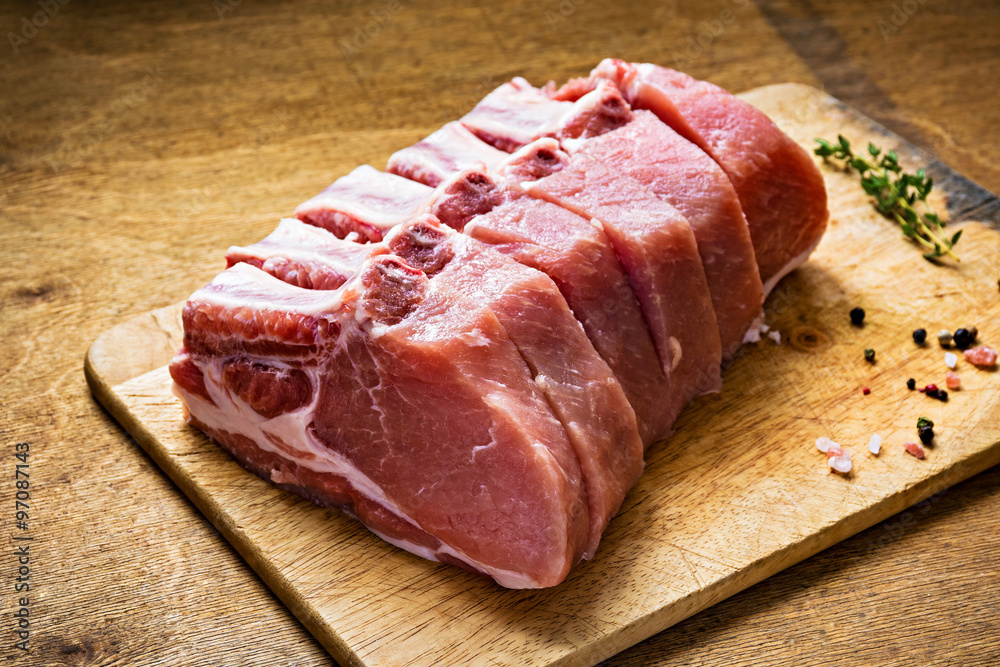 Fresh raw pork chop meat on cutting board, close up