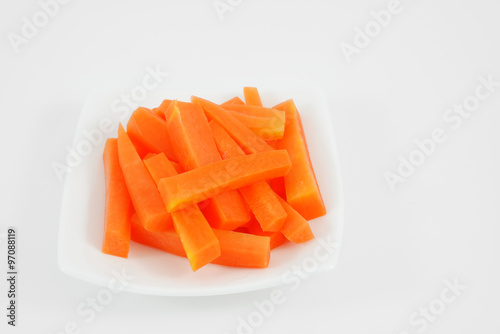 The fresh orange carrot sticks on the white small dish.