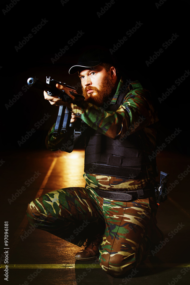 Soldier in camouflage with is holding rifle at dark background Soldier in camouflage with is holding rifle at dark background