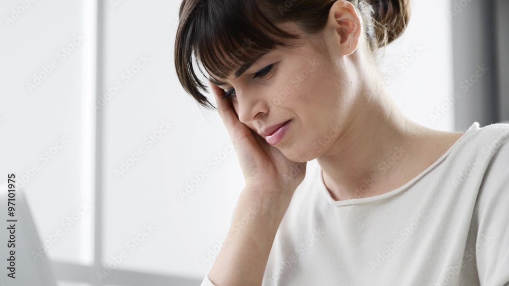 Tired young businesswoman working at office desk, she is having an headache and touching her temples Tired young businesswoman working at office desk, she is having an headache and touching her temples