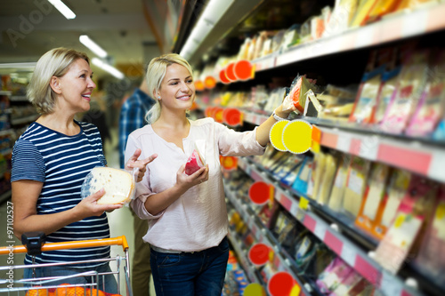 Adult girl with senior mother in cheese section of supermarket photo