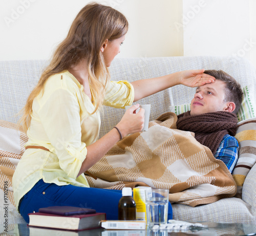 Wife taking care of young husband with flue at home
