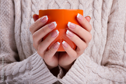 Woman holds an orange cup close up.