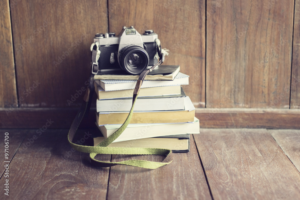 Obraz premium Old style camera on pile of books on wooden floor