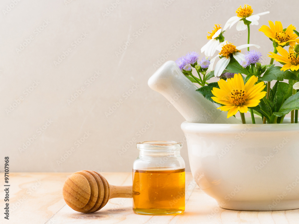 Honey and dropper with wild flowers on a wooden background Honey and dropper with wild flowers on a wooden background
