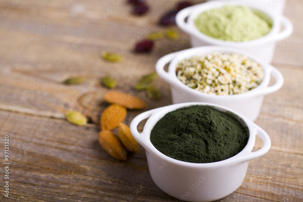Superfood raw seeds and powder. Body building powders and health food on wooden background. Superfood served in small bowls. Superfood raw seeds and powder. Body building powders and health food on wooden background. Superfood served in small bowls.