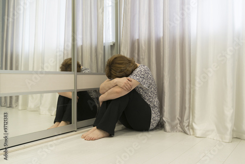 Woman with depression sitting in  corner of the room