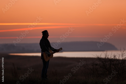 Man with guitar in sunset
