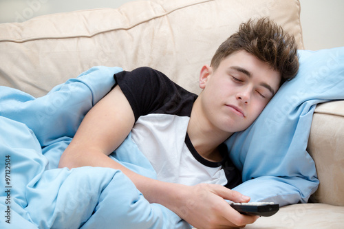 Photographie Teenage boy laying on a sofa watching sleeping