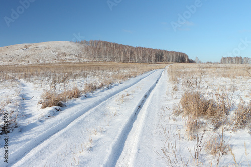 Snow automobile road going near a hill Bald, Bugotaksky hills, the Novosibirsk region, Russia