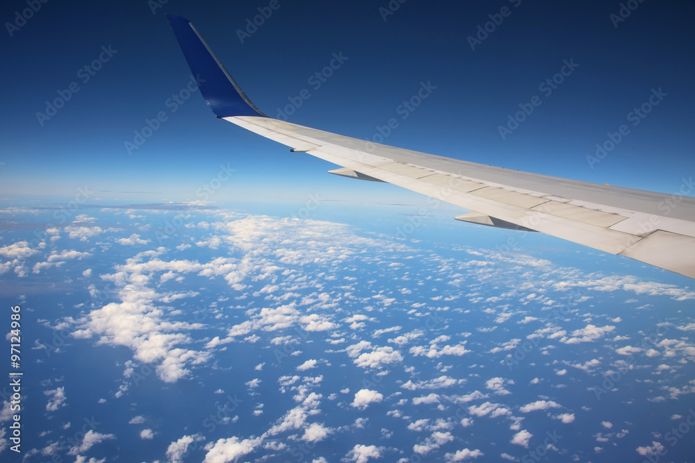 Wing of airplane above white clouds Wing of airplane above white clouds