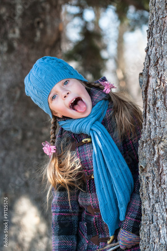 Girl behind the tree showing her funny face with tongue