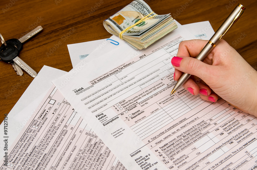 Obraz premium Woman hand filling income tax forms 1040