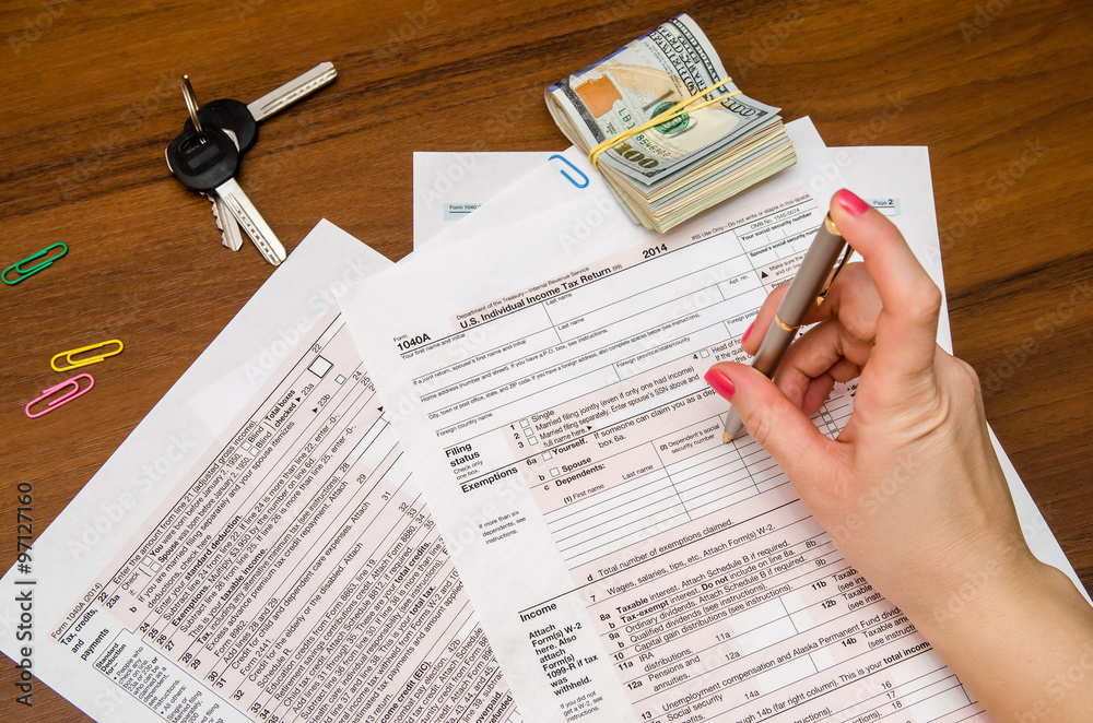 Obraz premium Woman hand filling income tax forms 1040