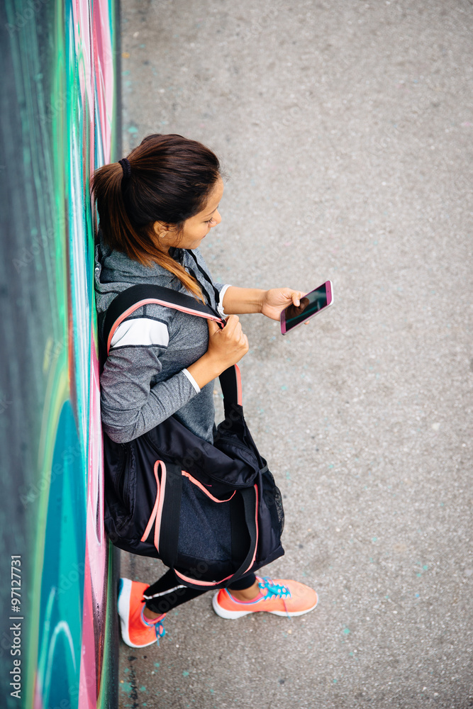 Obraz premium Urban sporty woman texting on smartphone