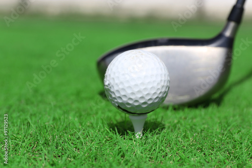 Golf club and ball on a green grass, close up