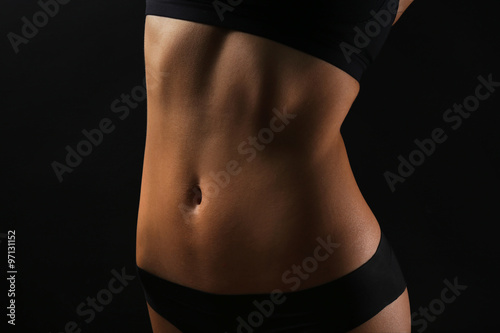 Slim female body in nice black lingerie on dark background
