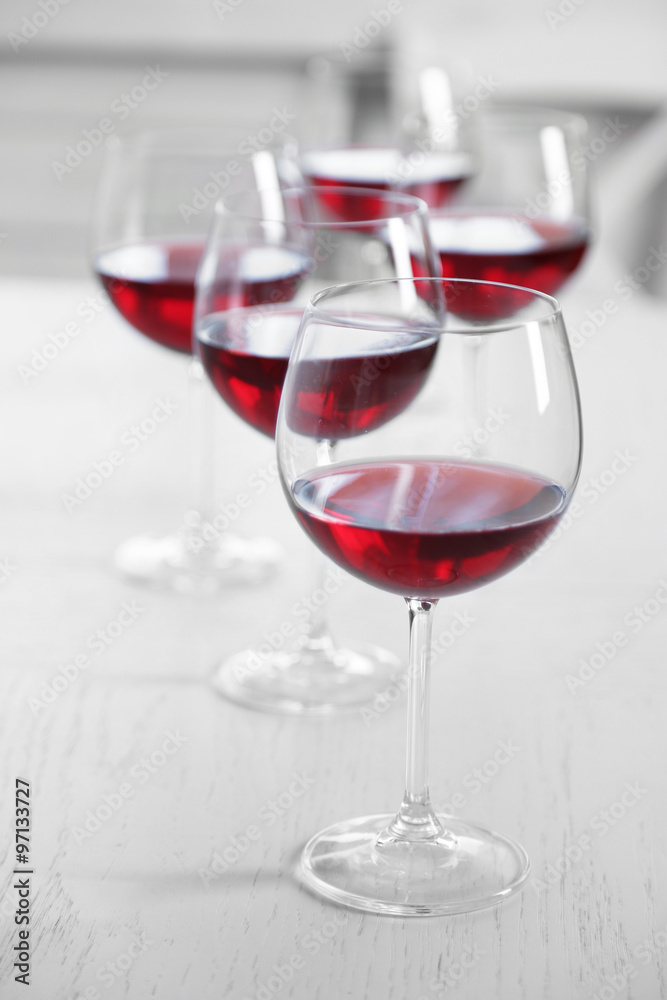 Glasses of red wine on table on bright background Glasses of red wine on table on bright background