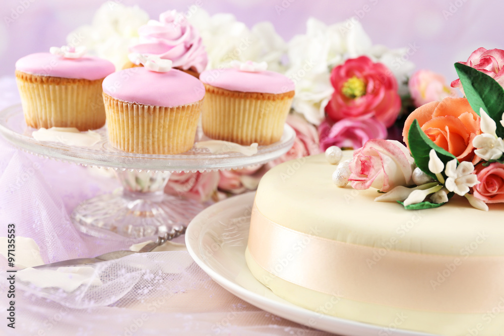 Cake with sugar paste flowers and cupcakes, on light background Cake with sugar paste flowers and cupcakes, on light background