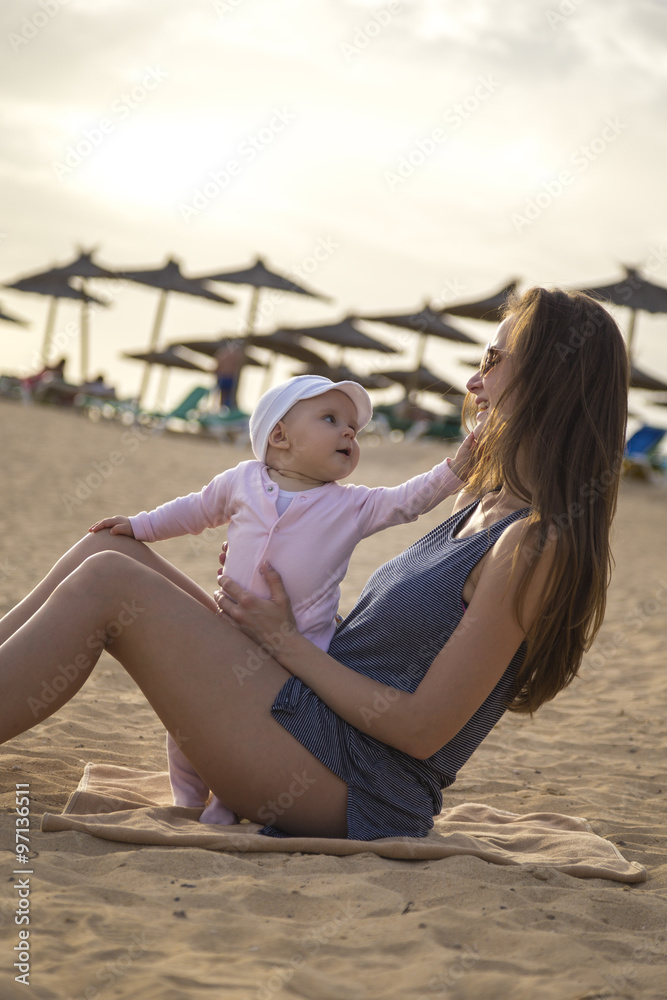 mother sitting on the beach with her daughter mother sitting on the beach with her daughter