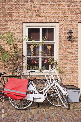 White classic bicycle parked against brick wall of an ancient house, Heusden, Netherlands.