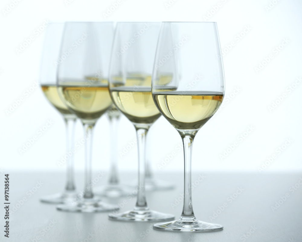 Wineglasses with white wine on wooden table on bright background Wineglasses with white wine on wooden table on bright background