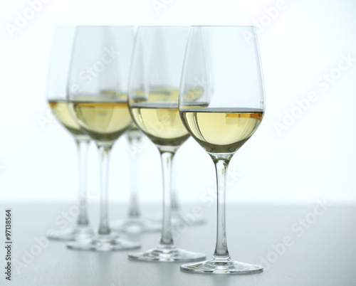 Wineglasses with white wine on wooden table on bright background