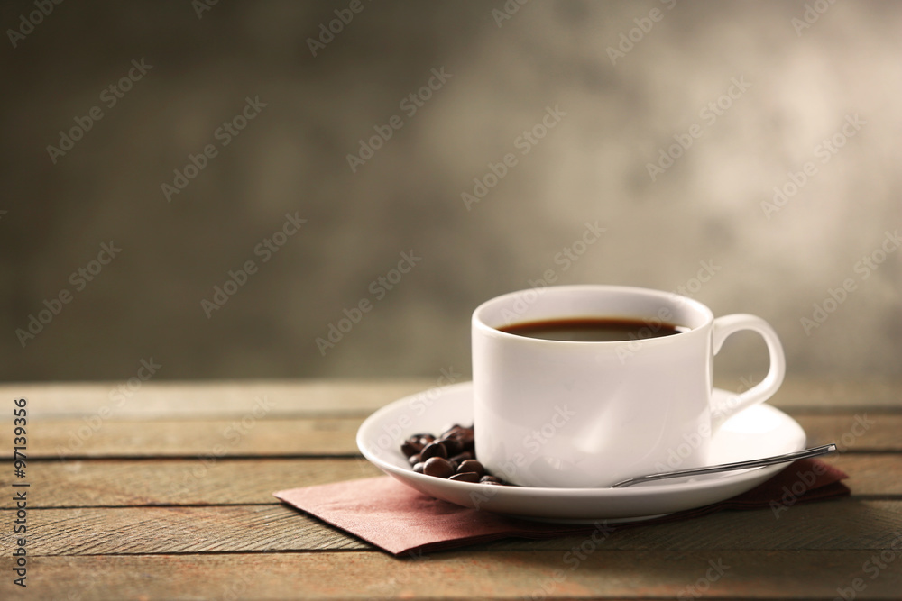Cup of coffee and coffee grains on wooden table, on gray background Cup of coffee and coffee grains on wooden table, on gray background