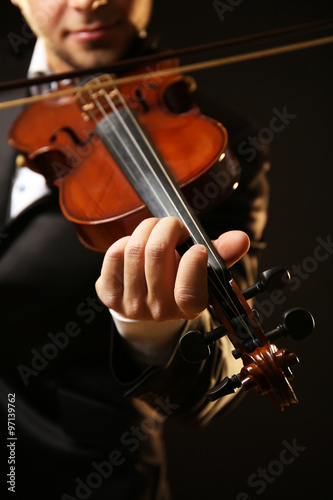 Musician plays violin on black background, close up