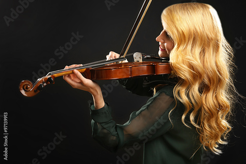 Musician plays violin on black background, close up